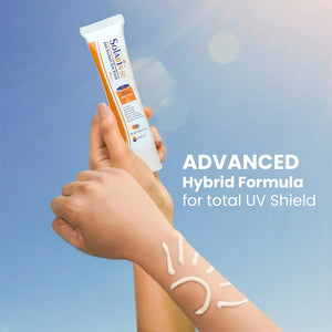 Person holding Safrin Skin Care Solarin 60 sunscreen with sun design on arm, blue sky background